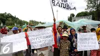 Beberapa warga mengangkat tulisan saat melakukan unjuk rasa di depan Istana Negara, Jakarta, Senin (17/1). Dalam aksinya, mereka menolak pembangunan mega proyek Pembangkit Listrik Tenaga Uap (PLTU) di Cirebon. (Liputan6.com/Helmi Fithriansyah)