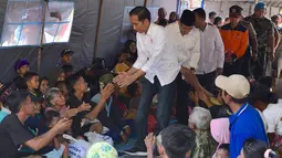 Presiden Joko Widodo atau Jokowi bersama Gubernur NTB Tuan Guru Bajang (TGB) Zainul Majdi menyapa warga saat mengunjungi korban gempa di lapangan Desa Madayin, Sambelia, Lombok Timur, NTB, Senin (30/7). (Agus Suparto/Indonesian Presidential Palace/AFP)