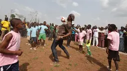 Mantan penyerang Chelsea, Didier Drogba berusaha mengontrol bola saat bermain dengan murid-murid saat peresmian sekolah di Pokou-Kouamekro, dekat Gagnoa, Pantai Gading tengah barat (17/1). (AFP Photo/Sia Kambou)