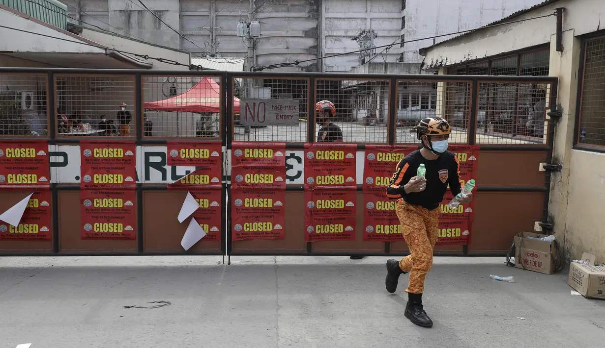 Seorang petugas pemadam kebakaran memegang botol air di depan Pabrik Es TP Marcelo di Navotas, Filipina, Kamis (4/2/2021). Lebih dari 90 warga dan karyawan pabrik dibawa ke rumah sakit setelah terpapar gas amonia yang bocor, yang digunakan sebagai pendingin. (AP Photo/ Aaron Favila)