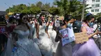 Wanita Myanmar memakai gaun pengantin memegang plakat selama demonstrasi menentang kudeta militer 1 Februari di Yangon (10/2/2021). (AFP/ Ye Aung Thu)
