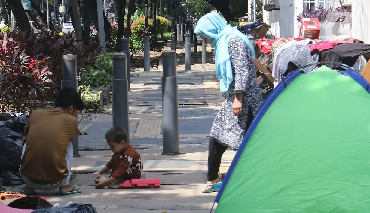 Pencari suaka beraktivitas di trotoar kantor UNHCR, Jalan Kebon Sirih, Jakarta, Sabtu (1/5/2021). Para pencari suaka itu menuntut Komisi Tinggi PBB untuk Pengungsi (UNHCR) meminta kejelasan atas status dan memperhatikan nasib mereka selama hidup di Indonesia. (Liputan6.com/Herman Zakharia)
