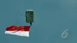Seorang prajurit membentangkan bendera Merah Putih saat melakukan aksi terjun payung 18 lapis dalam perayaan HUT ke-63 Kopassus di Cijantung, Jakarta, Rabu (29/4/2015). (Liputan6.com/Herman Zakharia)