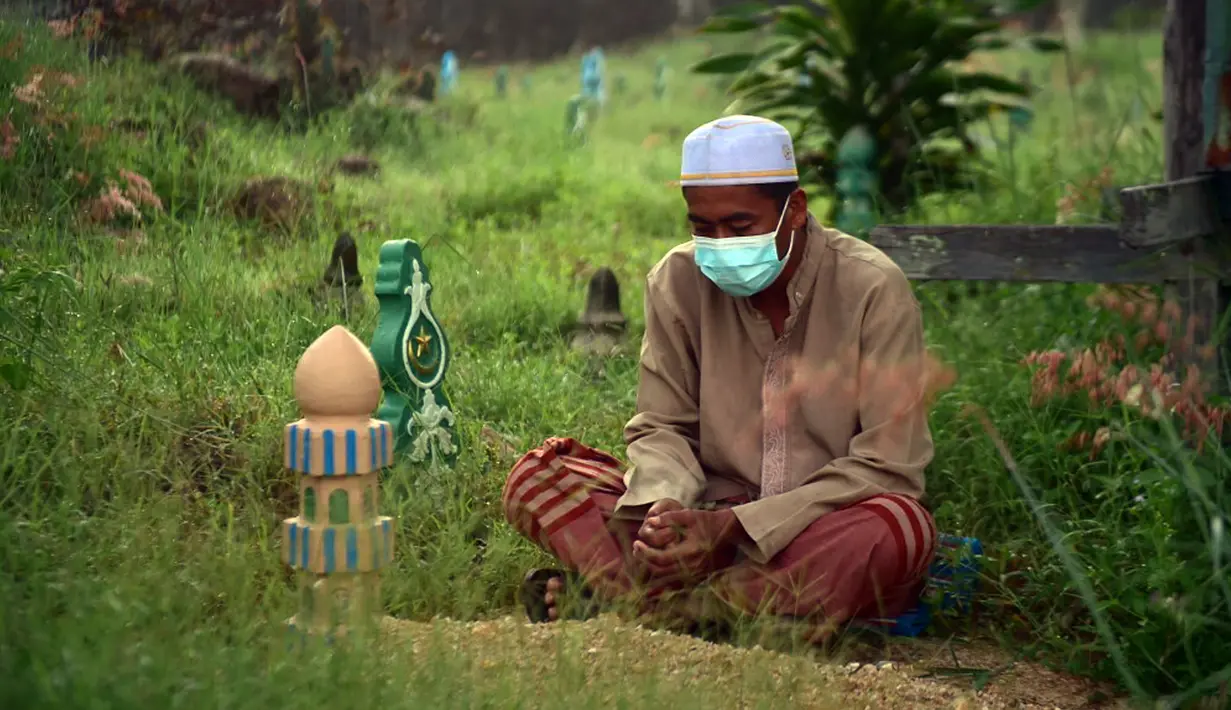 Seorang pria berdoa di sebelah makam kerabat saat perayaan Hari Raya Idul Adha di sebuah pemakaman di Provinsi Narathiwat, Thailand, Rabu (21/7/2021). Setiap Idul Adha atau hari besar Islam lainnya, sebagian warga banyak mendatangi kuburan untuk mendoakan keluarganya. (Madaree TOHLALA/AFP)