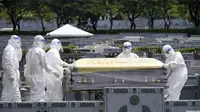 Petugas kesehatan menggunakan alat pelindung diri (APD) membawa peti jenazah korban Covid-19 (AP/Arsip)