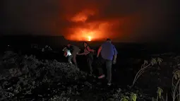 Warga berjalan kaki menaiki lereng untuk melihat guguran lava pijar yang keluar dari gunung api Piton de la Fournaise atau Peak of the Furnace di Pulau Reunion, Samudera Hindia, Prancis, Selasa (13/8/2019). Letusan Piton de la Fournaise berlanjut hingga hari ketiga. (Richard BOUHET/AFP)