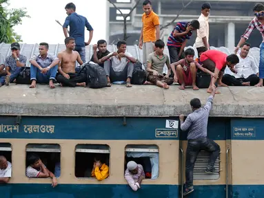 Seorang penumpang berusaha naik ke atap kereta api saat akan pulang kampung di stasiun kereta api di Dhaka, Bangladesh, (22/6). Ribuan yang bekerja di Dhaka pulang ke kampung halamannya untuk merayakan lebaran bersama keluarganya. (AP Photo/A.M.Ahad)