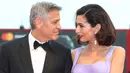 Pasangan selebritis, George dan Amal Clooney berpose untuk fotografer di Venice Film Festival ke-74, Italia, 2 September 2017.  Sentuhan glamor Amal semakin terasa berkat anting berbatu safir dan giok dari Lorraine Schwartz. (Joel Ryan/Invision/AP)
