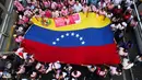 Sejumlah warga mengibarkan bendera nasional Venezuela saat mengikuti pawai yang diselenggarakan pemerintah untuk meningkatkan kesadaran terhadap kanker payudara dalam rangka Bulan Peduli Kanker Payudara atau Pink Month di Caracas, Venezuela, Kamis (22/10/2026). (AP Photo/Pedro Mattey)