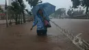 Seorang Wanita saat berjalan melewati banjir di jalan Letjen Suprapto Cempaka Putih, Jakarta, Senin (9/2/2015). (Liputan6.com/Herman Zakharia)
