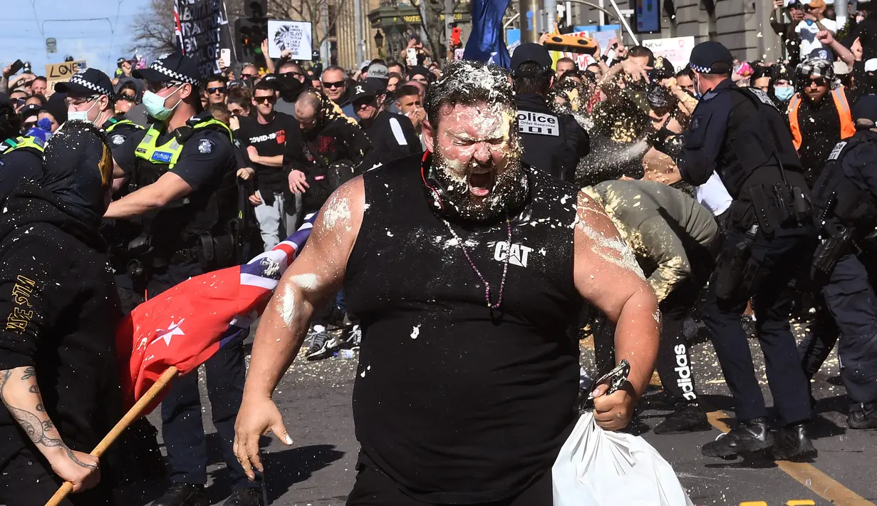Seorang pengunjuk rasa bereaksi dari semprotan merica yang digunakan oleh polisi selama demonstrasi anti-lockdown di tengah penguncian keenam kota untuk menahan wabah virus corona di Melbourne (21/8/2021). (AFP/William West)