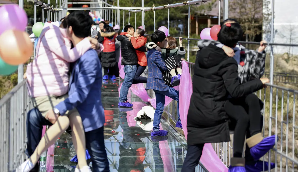 Sejumlah pasangan berciuman diatas sebuah jembatan kaca saat mengikuti kontes berciuman di Hari Valentine di Pingjiang, Provinsi Hunan, China (14/2). (STR / AFP)