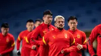 Aloisio dos Santos Goncalves dari China, juga dikenal sebagai Luo Guofu (depan) melakukan pemanasan saat mengikuti sesi latihan di Stadion Saitama, Jepang, Rabu (26/1/2022). China akan menghadapi Jepang pada Kualifikasi Piala Dunia 2022 Grup B Zona AFC. (AFP/Philip Fong)