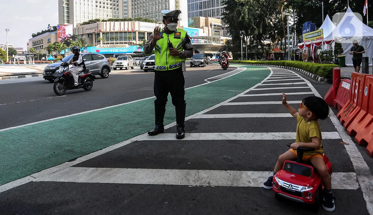 Polisi saat berbincang dengan seorang anak yang sedang mengendarai mobil mainan di  di kawasan Bundaran Hotel Indonesia, Jakarta, Indonesia pada Sabtu 22 April 2023. (Liputan6.com/Johan Tallo)