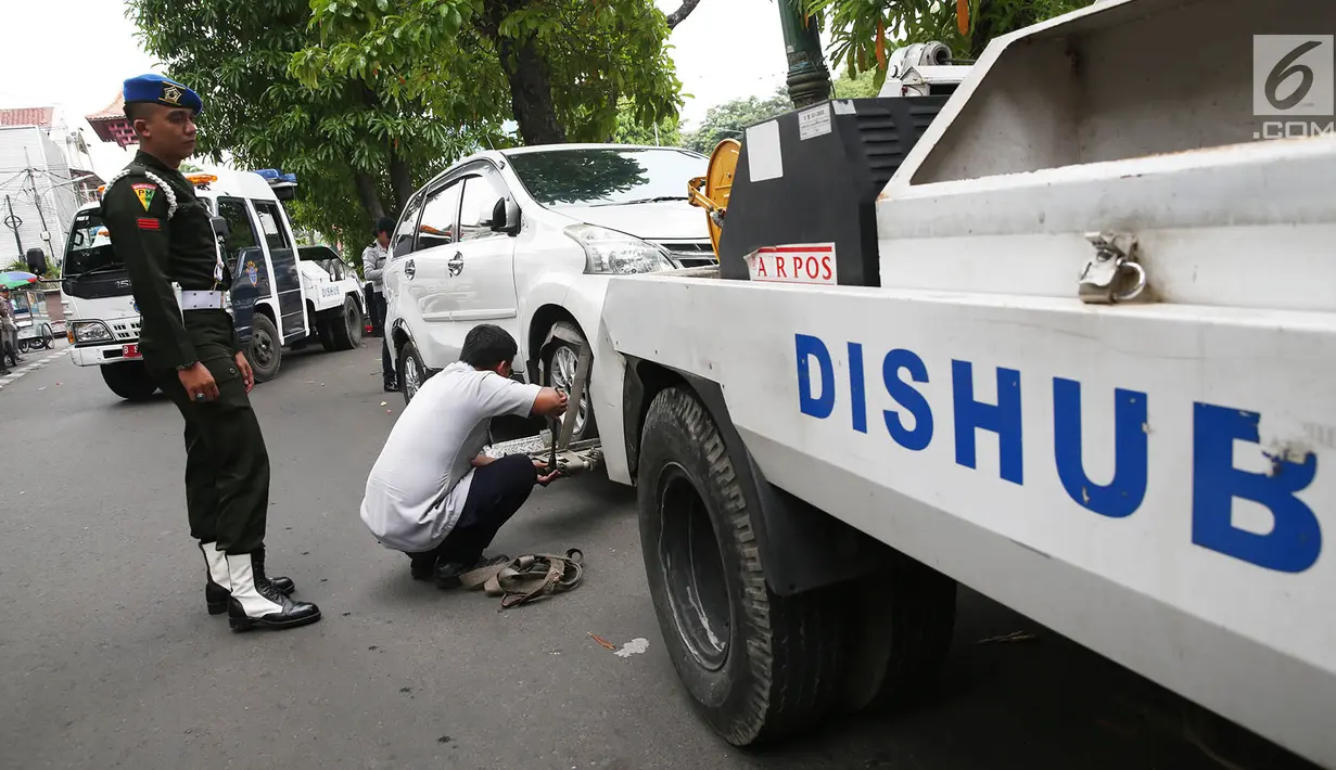 Petugas Dinas Perhubungan mengaitkan kendaraan pada mobil derek di kawasan Pasar Baru, Jakarta, Kamis (14/12). Parkir sembarang di pinggir jalan ini membuat kesemrawutan dan menimbulkan kemacetan. (Liputan6.com/Immanuel Antonius)