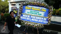 Pekerja membawa karangan bunga duka cita wafatnya Ketua KPU Husni Kamil Manik di Kompleks KPU, Jakarta, Jumat (8/7). Sejumlah pejabat tinggi negara hadir melayat jenazah Husni Kamil Manik yang wafat pada Kamis (7/7). (Liputan6.com/Helmi Fithriansyah)