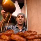 Pedagang menambahkan madu pada Chebakia, kuliner asli dari Maroko, yang dijajakan di Ibu Kota Maroko, Rabat, 6 Juni 2016. Kehadiran penganan ini menandai datangnya bulan Ramadan atau peristiwa penting. (Fadel SENNA/AFP)