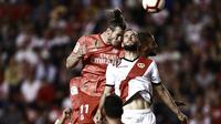 Duel penyerang Real Madrid, Gareth Bale (merah), dengan gelandang Rayo Vallecano, Mario Suarez saat kedua tim berjumpa dalam laga lanjutan La Liga di Vallecas Stadium, Puente de Vallecas, Senin dini hari WIB (29/4/2019).  (AFP/Benjamin Cremel)