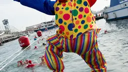 Seorang peserta dalam kostum badut melompat ke air saat  kompetisi renang Copa Nadal di Port Vell Barcelona, Selasa (25/12). Lomba renang tradisonal ini berlangsung pada hari natal sejak 1908 di pelabuhan tua Barcelona. (Josep LAGO / AFP)