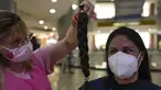 Maryori Araque (kanan) melihat sehelai rambutnya setelah dipotong dalam acara Bulan Peduli Kanker Payudara di sebuah mal di Caracas, Venezuela, Sabtu (16/10/2021). Rambut yang dipotong akan disumbangkan untuk membuat wig bagi pasien kanker. (AP Photo/Ariana Cubillos)