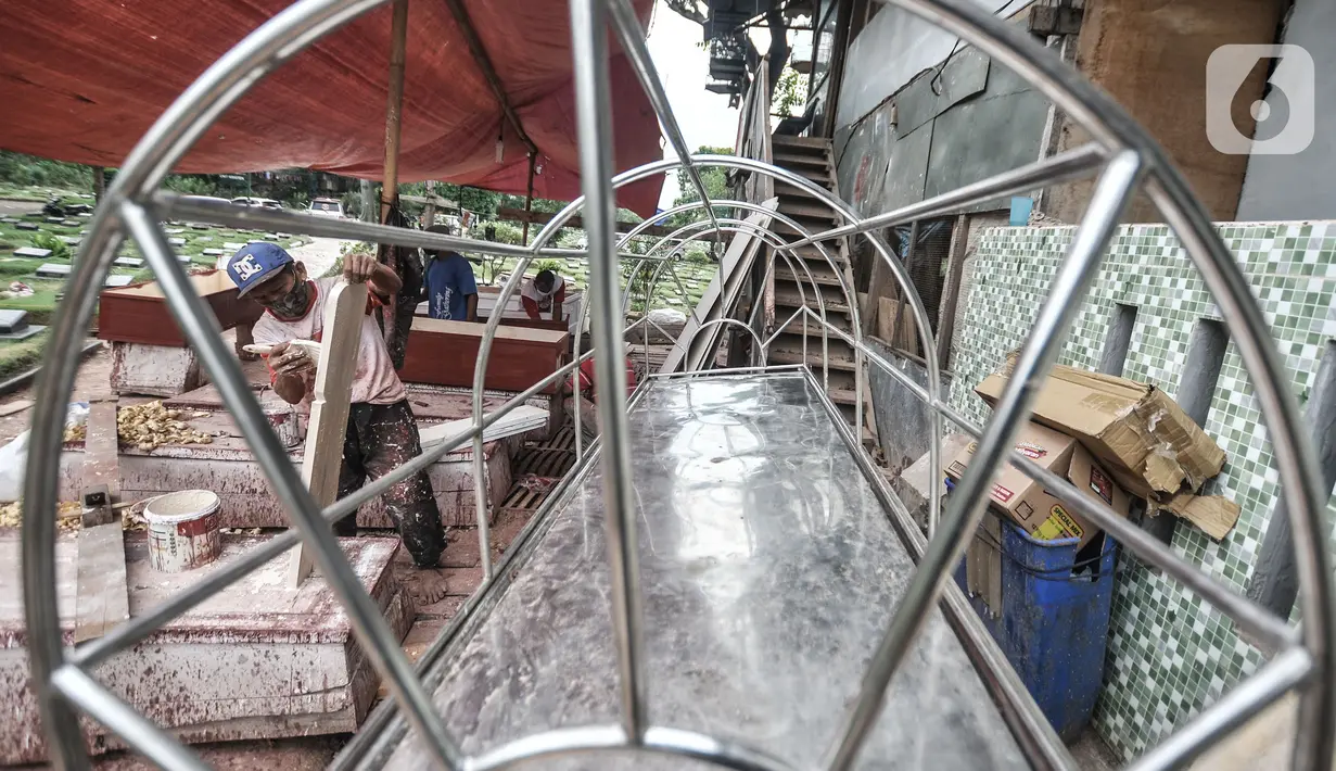 Pekerja menyelesaikan pembuatan peti jenazah untuk pasien Covid-19 di TPU Pondok Kelapa, Jakarta, Selasa (13/7/2021). Menurut pekerja, dalam sehari mampu membuat hingga 50 peti jenazah dari ratusan pesanan dari pihak rumah sakit, baik di Jakarta maupun luar kota. (merdeka.com/Iqbal S Nugroho)