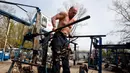 Seorang pria berlatih mengangkat beban tubuhnya di outdoor gym atau pusat kebugaran terbuka di tepi Sungai Dnipro, Kiev, Ukraina, Kamis (18/4). Meskipun kurang mewah, tempat kebugaran ini ternyata banyak peminatnya. (AP Photo/Efrem Lukatsky)