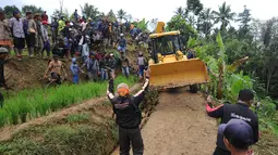 Warga memandu alat berat melalui jalan kecil menuju lokasi longsor di Dusun Cimapag, Sirnaresmi, Cisolok, Sukabumi, Jawa Barat, Selasa (1/1). Lokasi terpencil dan sempitnya jalan menyebabkan alat berat sulit masuk lokasi longsor. (Merdeka.com/Arie Basuki)