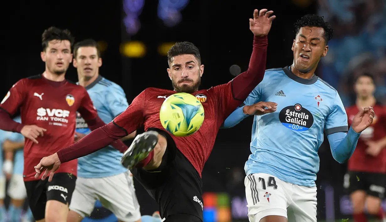 Pemain Valencia Cristiano Piccini (tengah) berebut bola dengan pemain Celta Vigo Renato Tapia (kanan) pada pertandingan Liga Spanyol di Stadion Balaidos, Vigo, Spanyol, 5 Desember 2021. Valencia menang 2-1. (MIGUEL RIOPA/AFP)