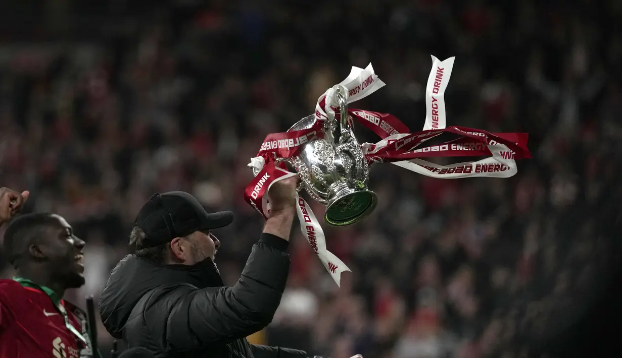 Pelatih Liverpool, Jurgen Klopp mengangkat piala Carabao Cup saat melakukan selebrasi usai pertandingan Final Carabao Cup di Stadion Wembley, London, Senin (28/2/2022). Liverpool memenangkan adu penalti 11-10 setelah pertandingan berakhir imbang 0-0. (AP Photo/Alastair Grant)