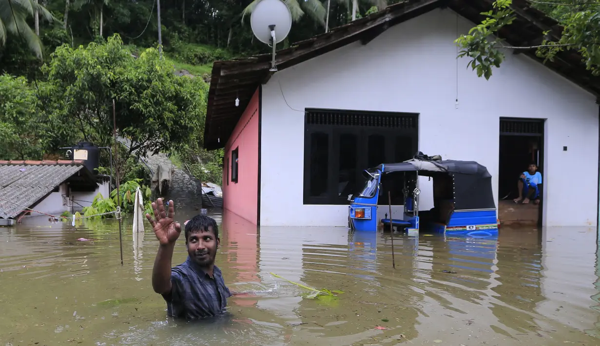 Seorang warga melambaikan tangan di dekat rumahnya yang dilanda banjir, Sri Lanka, Minggu (28/5). Atas bencana banjir dan longsor ini, Kementerian Luar Negeri Sri Lanka telah mengajukan permintaan bantuan dari PBB dan negara-negara tetangga. (AP Photo)