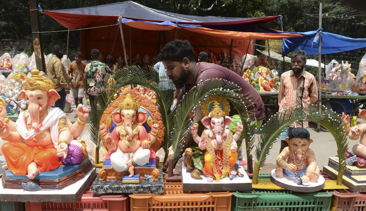 Seorang perajin memajang patung Dewa Ganesha untuk dijual di kios pinggir jalan di Hyderabad, India, Kamis (9/9/2021). Patung dewa Hindu berkepala gajah tersebut banyak dijual jelang Festival Ganesh Chaturthi. (NOAH SEELAM/AFP)