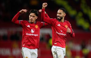 Lisandro Martinez (kiri) dan rekan setimnya, Matheus Cunha, memberikan apresiasi kepada suporter MU selepas duel melawan Newcastle United dalam lanjutan Liga Inggris 2025/2026 di Old Trafford, Sabtu (27/12/2025) dini hari WIB. (AP Photo/Dave Thompson)