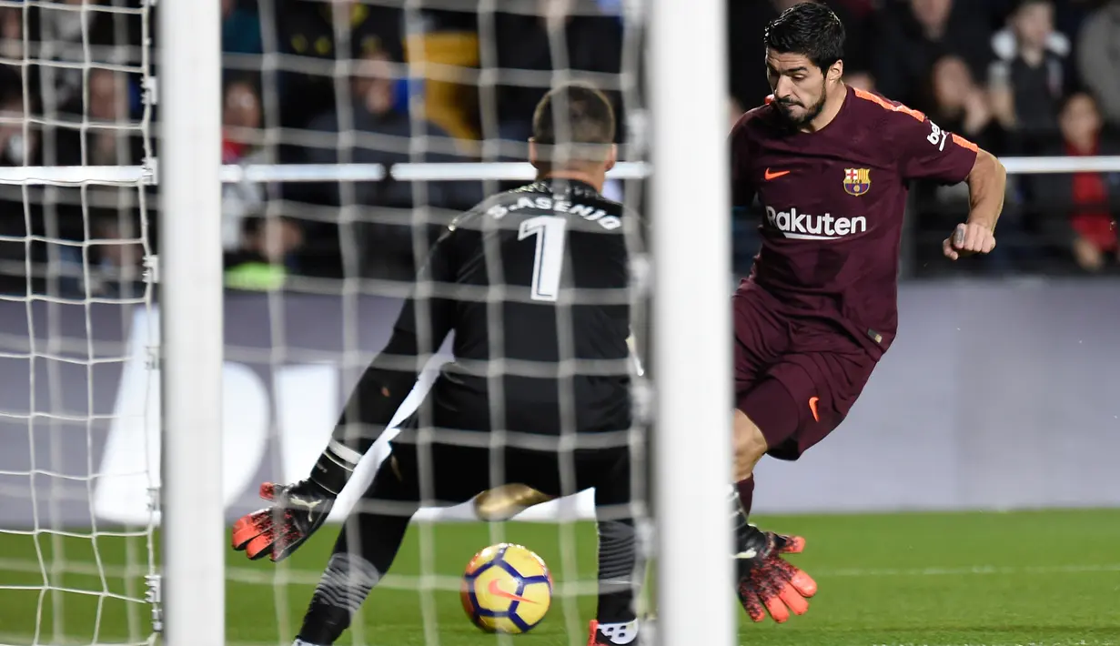 Pemain Barcelona, Luiz Suarez melakukan tendangan yang berusaha ditangkap kiper Villarreal, Sergio Asenjo pada jornada ke-15 La Liga di Stadion Ceramica, Minggu (10/12). Barca menyudahi pertandingan ini dengan kemenangan 2-0.  (JOSE JORDAN / AFP)