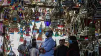 Orang Mesir melihat lentera tradisional yang dikenal dalam bahasa Arab sebagai "Fanous" menjelang bulan Ramadan di Sayeda Zainab, Kairo, 19 April 2020. Bagi warga Mesir membeli lentera sudah menjadi tradisi sejak berabad-abad walaupun kini virus corona tengah melanda dunia. (Mohamed el-Shahed/AFP)