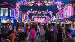 Pejalan kaki melintasi jalan yang dihiasi dekorasi meriah menjelang Diwali, festival cahaya bagi umat Hindu, di distrik Little India di Singapura pada 23 Oktober 2020. (Photo by Roslan RAHMAN / AFP)
