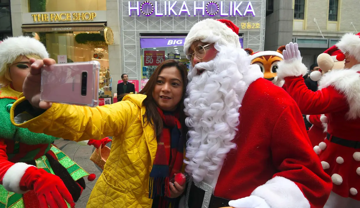 Seorang wanita berselfie dengan Santa Claus saat promosi musim Natal di distrik perbelanjaan di Seoul (13/11). Meski sebagian besar penduduknya adalah umat Budha, anak muda Korsel menikmati perayaan musim Natal tersebut. (AFP Photo/Jung Yeon-Je)