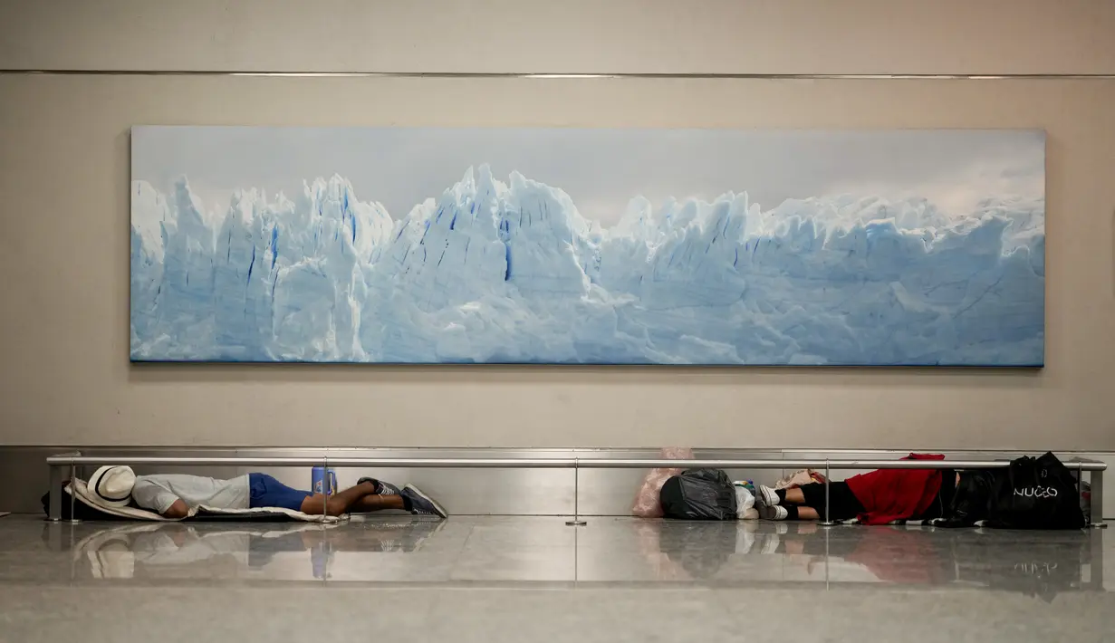 Para tunawisma tidur di bawah foto Gletser Perito Moreno di bandara internasional Jorge Newbery, umumnya dikenal sebagai Aeroparque, di Buenos Aires, Argentina, Kamis, 6 April 2023. (AP Photo/Natacha Pisarenko)