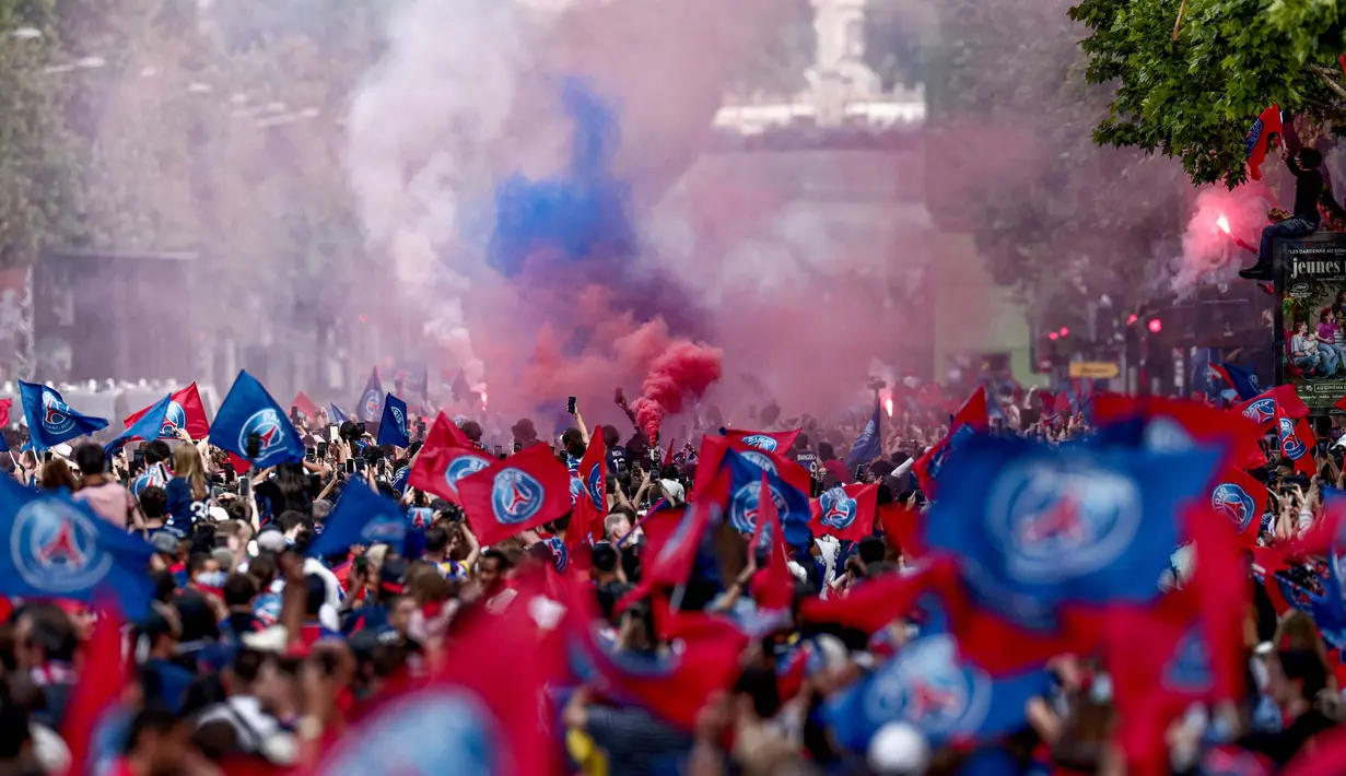 Ribuan pendukung dengan mengenakan atribut PSG menunggu kedatangan bus yang membawa para pemain melewati jalan Champs-Elysees. (Thibaud MORITZ/AFP)