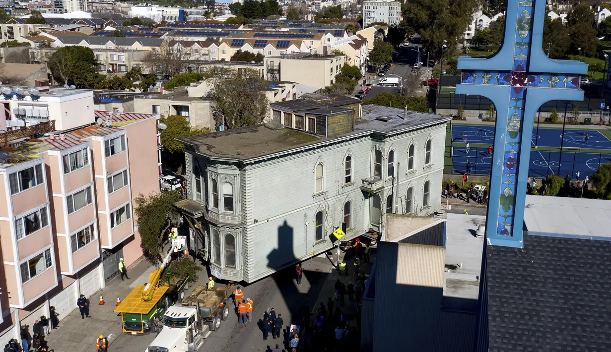Sebuah truk menarik rumah bergaya Victoria yang dibangun pada tahun 1882 di jalanan San Francisco, Minggu (21/2/2021). Warga berbaris di trotoar untuk mengambil foto saat rumah itu berjalan dengan kecepatan 1,7 km/jam ke 635 Fulton St. (AP Photo/Noah Berger)