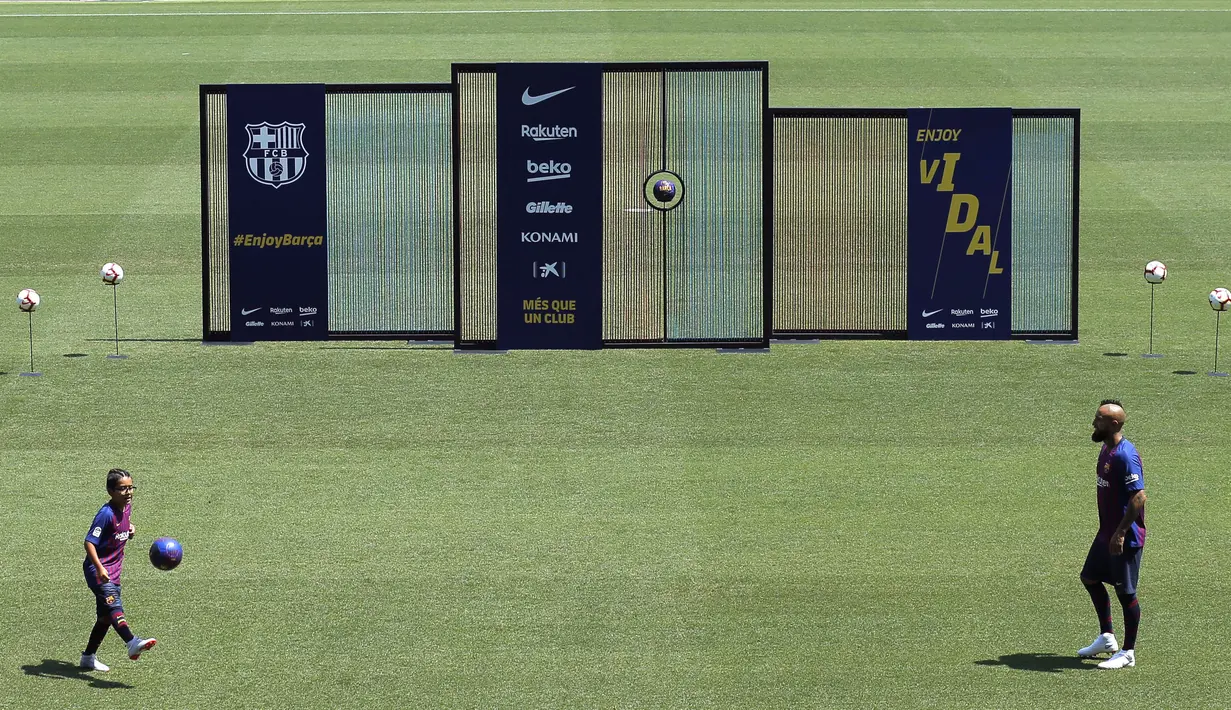 Pemain baru Barcelona, Arturo Vidal, bersama anaknya Alonso, saat perkenalan di Stadion Camp Nou, Senin, (7/8/2018). Barcelona merogoh kocek sebesar 19 juta euro untuk mengamankan jasa pria berkebangsaan Cile itu. (AP/Manu Fernandez)