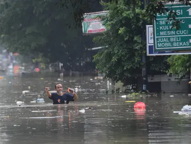 Warga berjalan di tengah banjir di Perumahan Vila Nusa Indah 3, Kabupaten Bogor, Jawa Barat, Selasa (4/3/2025). (merdeka.com/Arie Basuki)