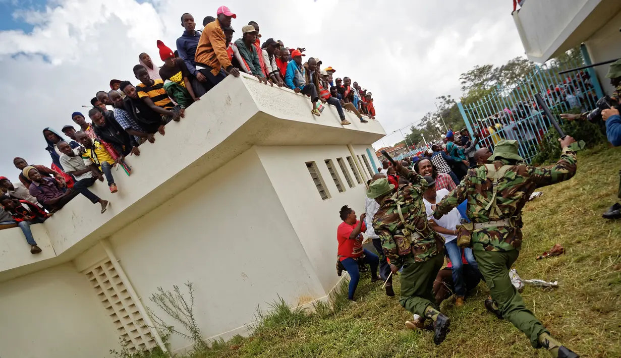 Polisi Kenya berusaha membubarkan pendukung Presiden Uhuru Kenyatta di Nairobi, Kenya (28/11). Para pendukung ini memaksa masuk untuk mengikuti pelantikan Presiden Kenya Uhuru Kenyatta. (AP Photo / Ben Curtis)
