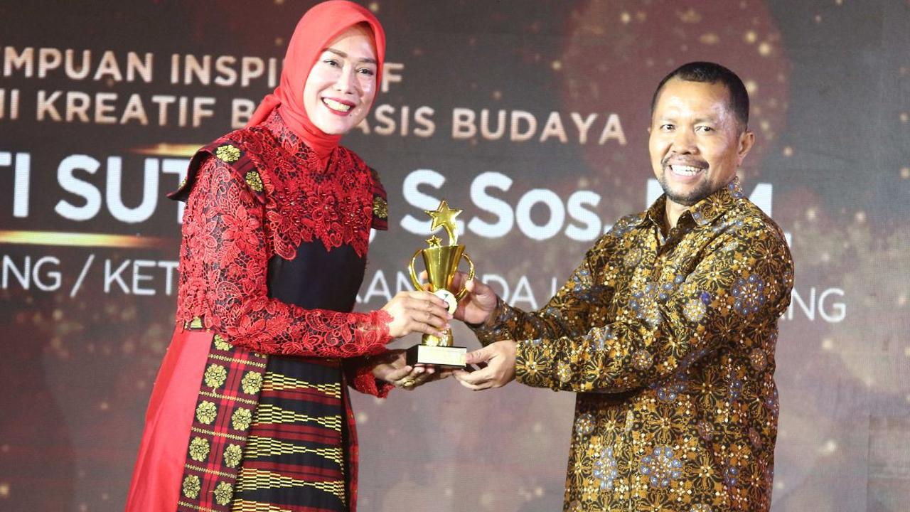 Direktur Konten KLY Wenseslaus Manggut memberikan penghargaan kepada Ketua DEKRANASDA Kota Malang, Widayati Sutiaji dalam Anugrah Inspiratif Liputan6.com kategori perempuan inspiratif pegiat ekonomi kreatif berbasis budaya di Jakarta, Sabtu (8/7/2023).