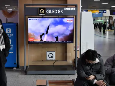 Seorang perempuan berjalan melewati layar televisi yang menayangkan siaran berita dengan rekaman file uji coba rudal Korea Utara, di sebuah stasiun kereta api di Seoul, Sabtu (31/12/20220). Korea Utara menutup akhir tahun 2022 dengan menembakkan tiga rudal balistik jarak pendek pada hari Sabtu, kata militer Korea Selatan. (Jung Yeon-je / AFP)