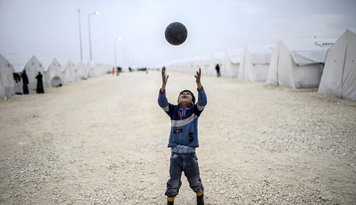 Bocah Syria bermain sepak bola di kamp pengungsian di Suruc, Propinsi Sanliurfa. (AFP PHOTO / BULENT KILIC)