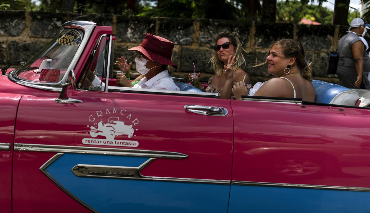 Turis menikmati mojito saat bepergian dengan mobil antik Amerika selama tur kota Varadero, Kuba, pada Rabu (29/9/2021). Pihak berwenang di Kuba mulai melonggarkan pembatasan COVID-19 di beberapa kota seperti Havana dan Varadero. (AP Photo/Ramon Espinosa)