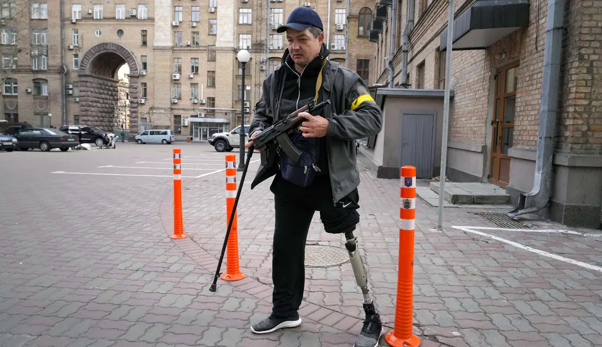 Seorang pria pertahanan sipil bersenjata berpatroli di jalan yang kosong karena jam malam di Kiev, Ukraina, Minggu (27/2/2022). Pihak berwenang Ukraina mengatakan bahwa pasukan Rusia telah memasuki kota terbesar kedua di Ukraina Kharkiv dan pertempuran di jalan-jalan. (AP Photo/Efrem Lukatsky)