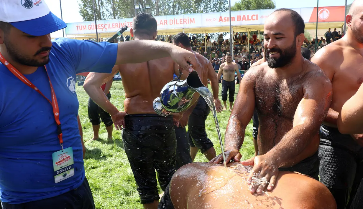 Pegulat Pehlivan disirami minyak sebagai persiapan untuk berkompetisi dalam turnamen Karrestcek Oil Wrestling ke-25 di Ankara (15/9/2019). Gulat minyak ini oleh Altındag Municipality. (AFP Photo/Adem Altan)