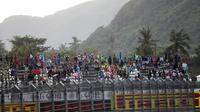 Penonton kehujanan saat hujan lebat sebelum Race 2 WSBK Mandalika 2021 di Pertamina Mandalika International Street Circuit, Lombok, Nusa Tenggara Barat, Minggu (21/11/2021). Balapan dilanjutkan pukul 15.30 WIB atau 16.30 Wita dan hanya digelar 12 lap. (AP Photo/Achmad Ibrahim)