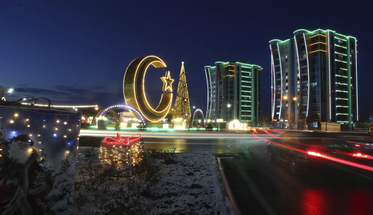 Pohon Natal, bulan sabit, dan bangunan apartemen yang didekorasi untuk perayaan Tahun Baru terlihat di alun-alun pusat di Argun, sekitar 17 km. (11 mil) timur Grozny, ibu kota republik Chechnya, Rusia, Kamis (23/12/2021). (AP Photo/Musa Sadulayev)